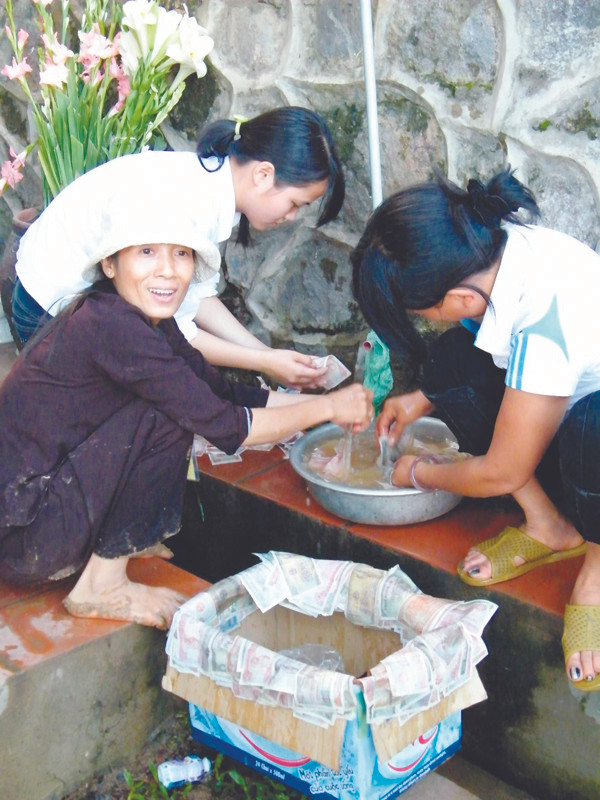 Cảnh rửa những đồng tiền bị “cúng” xuống đất ở một ngôi chùa vào dịp lễ hội. Ảnh: N.M.Hà