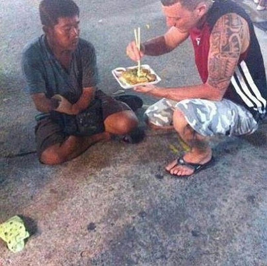 Một du khách người nước ngoài không ngại đút thức ăn cho người ăn xin
