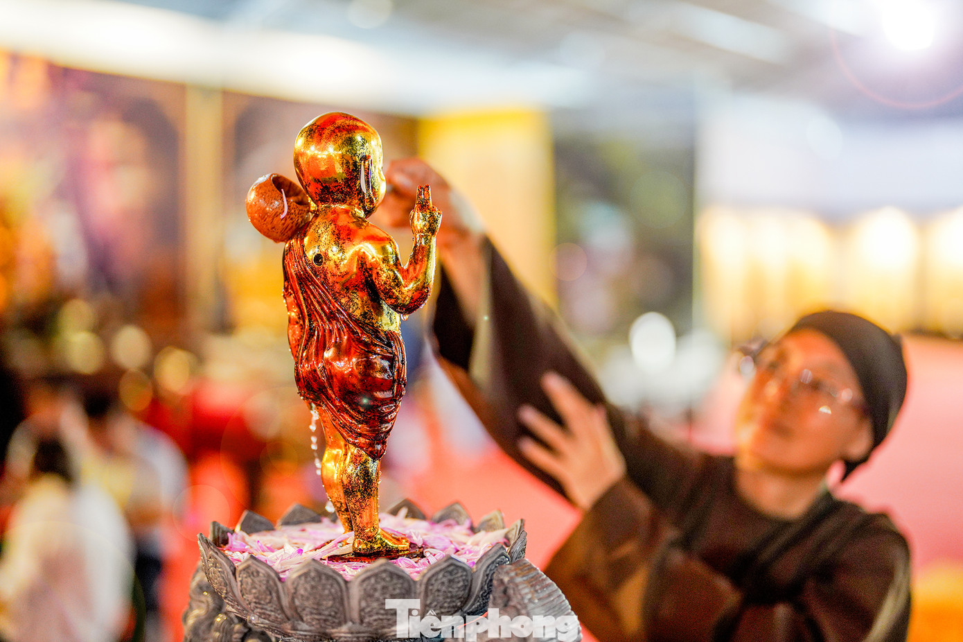 Một cư sĩ đang thực hiện nghi thức tắm Phật trong không gian triển lãm.