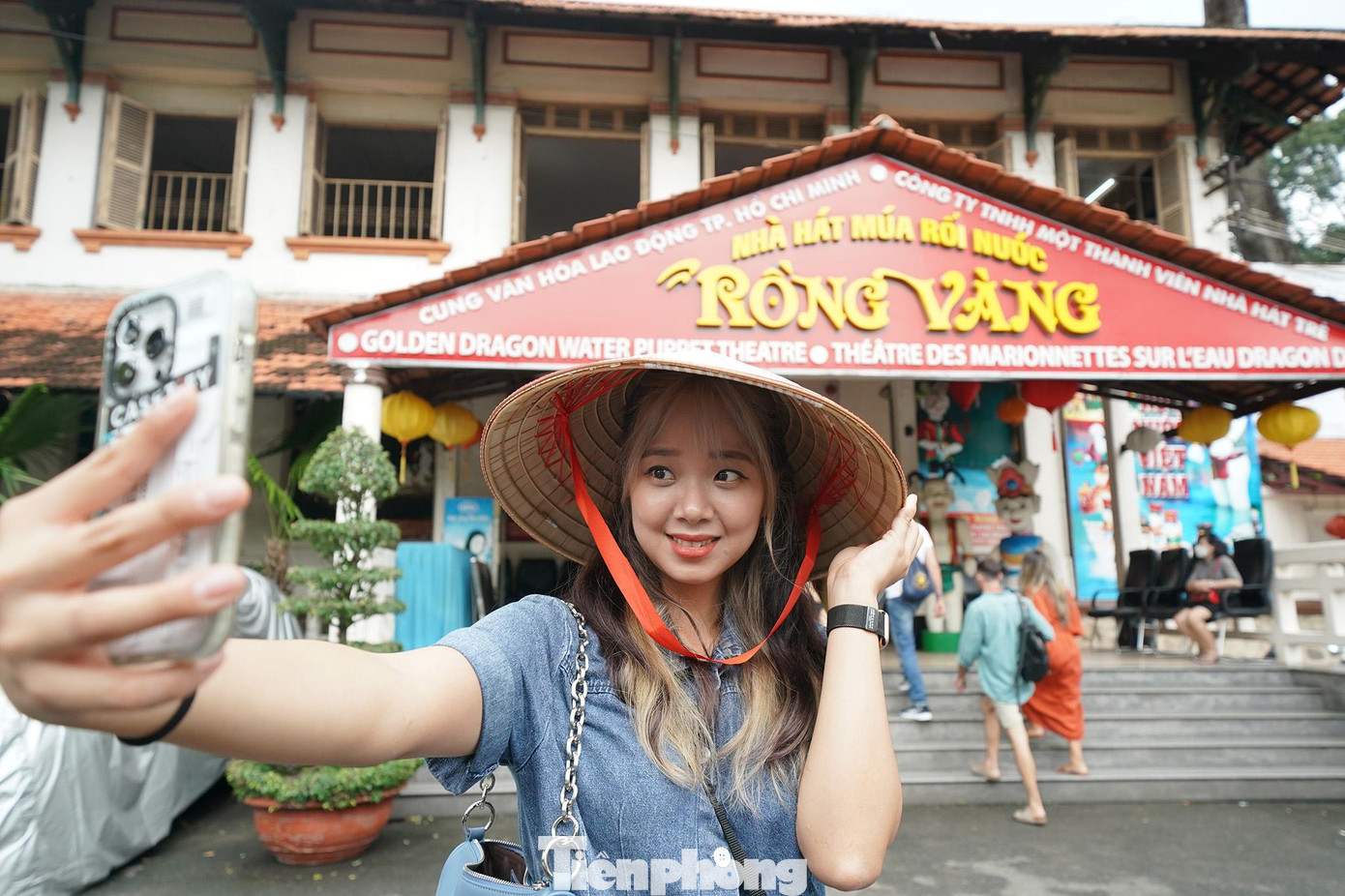 Cô nàng đến từ Hàn Quốc tranh thủ chụp ảnh trước khi vào xem múa rối. Nhà hát Múa rối nước Rồng Vàng là thương hiệu du lịch nổi bật của TPHCM. Trước đại dịch, khách du lịch quốc tế dù đi theo tour của các công ty lữ hành hay khách vãng lai tự do khi đến TPHCM đều chọn ghé qua Cung Văn hóa Lao động TPHCM xem rối nước. Ảnh hưởng bởi dịch bệnh, Rồng Vàng cũng là một trong những đơn vị nghệ thuật ngưng hoạt động đầu tiên khi thành phố triển khai các biện pháp chống dịch.