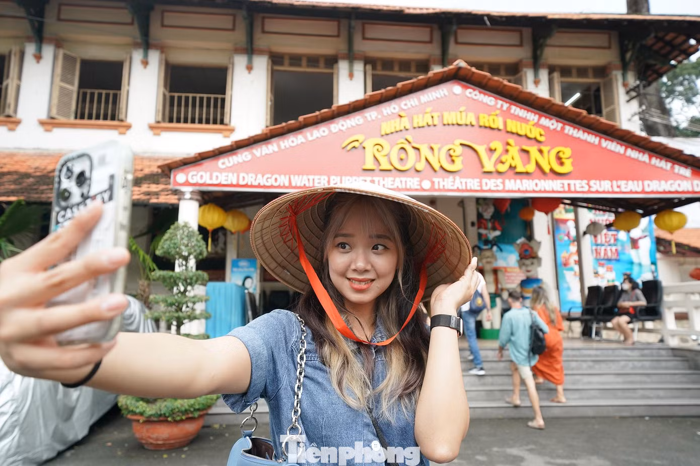 Cô nàng đến từ Hàn Quốc tranh thủ chụp ảnh trước khi vào xem múa rối. Nhà hát Múa rối nước Rồng Vàng là thương hiệu du lịch nổi bật của TPHCM. Trước đại dịch, khách du lịch quốc tế dù đi theo tour của các công ty lữ hành hay khách vãng lai tự do khi đến TPHCM đều chọn ghé qua Cung Văn hóa Lao động TPHCM xem rối nước. Ảnh hưởng bởi dịch bệnh, Rồng Vàng cũng là một trong những đơn vị nghệ thuật ngưng hoạt động đầu tiên khi thành phố triển khai các biện pháp chống dịch.