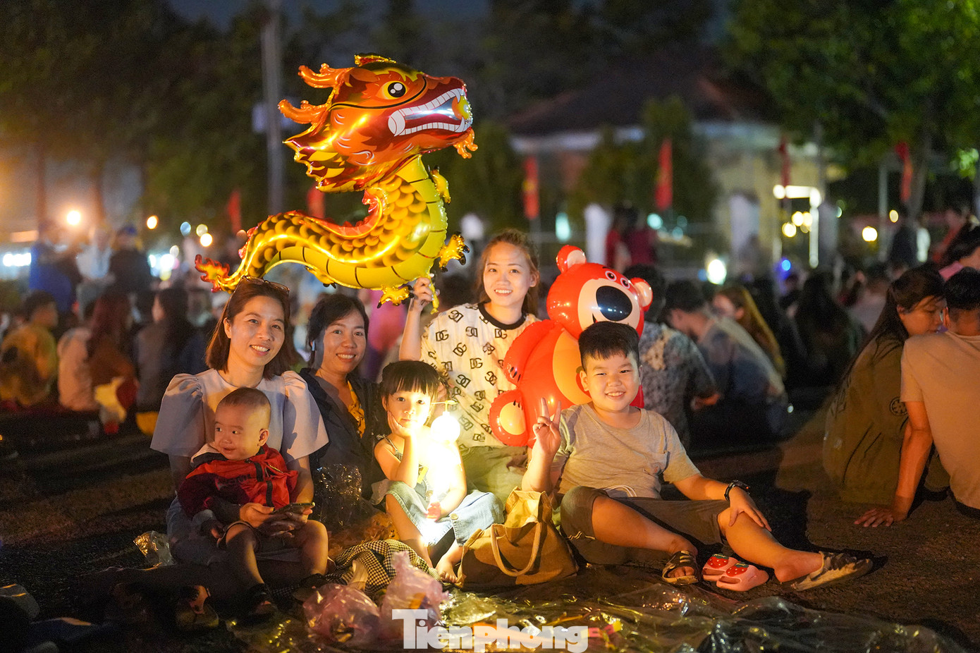 Chị Nguyễn Hoài Nhi, ngụ xã Bà Điểm, huyện Hóc Môn (TPHCM) ra đây từ 21h nên khá may mắn mới tìm được chỗ ngồi. Năm nay, cả gia đình chị Nhi có 7 thành viên ra đón giao thừa. "Ra hơi trễ mà tìm được chỗ ngồi vậy là quý rồi. Mấy năm trước bắn pháo hoa ở trung tâm không đi xem được vì vướng con nhỏ, nay gần nhà nên thuận tiện hơn", chị Nhi (ngoài cùng bên trái) chia sẻ.