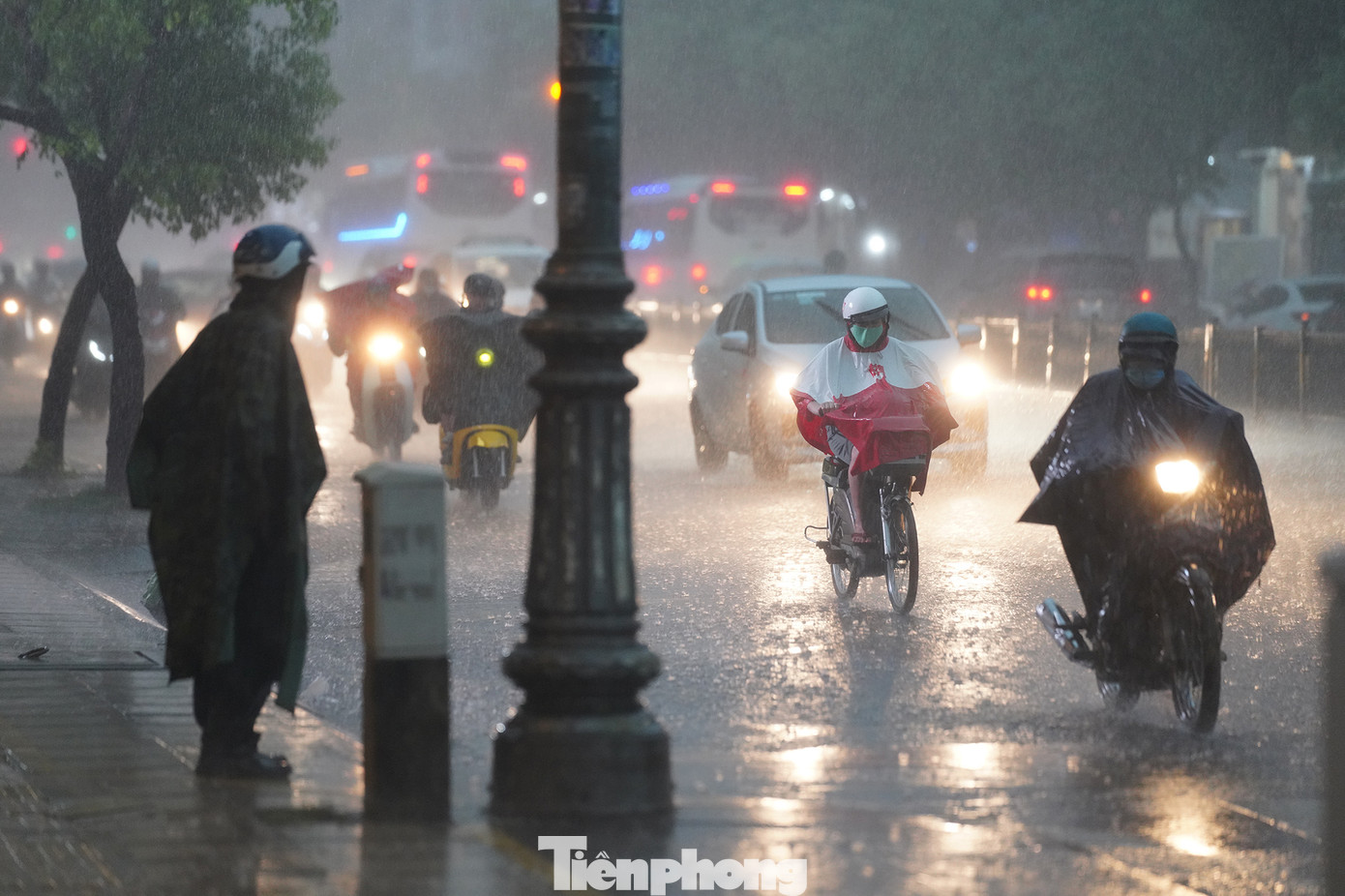 Một người đón xe buýt trong cơn mưa trước nhà Vãng Sanh chùa Vĩnh Nghiêm.