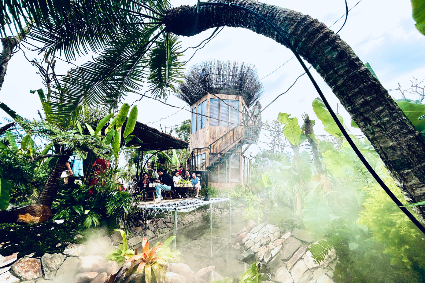 Quán cà phê được bao bọc, phủ kín bởi hệ thực vật phong phú, tạo cảm giác như một khu rừng nguyên sinh với khí hậu mát mẻ được tạo ra từ các máy phun sương.