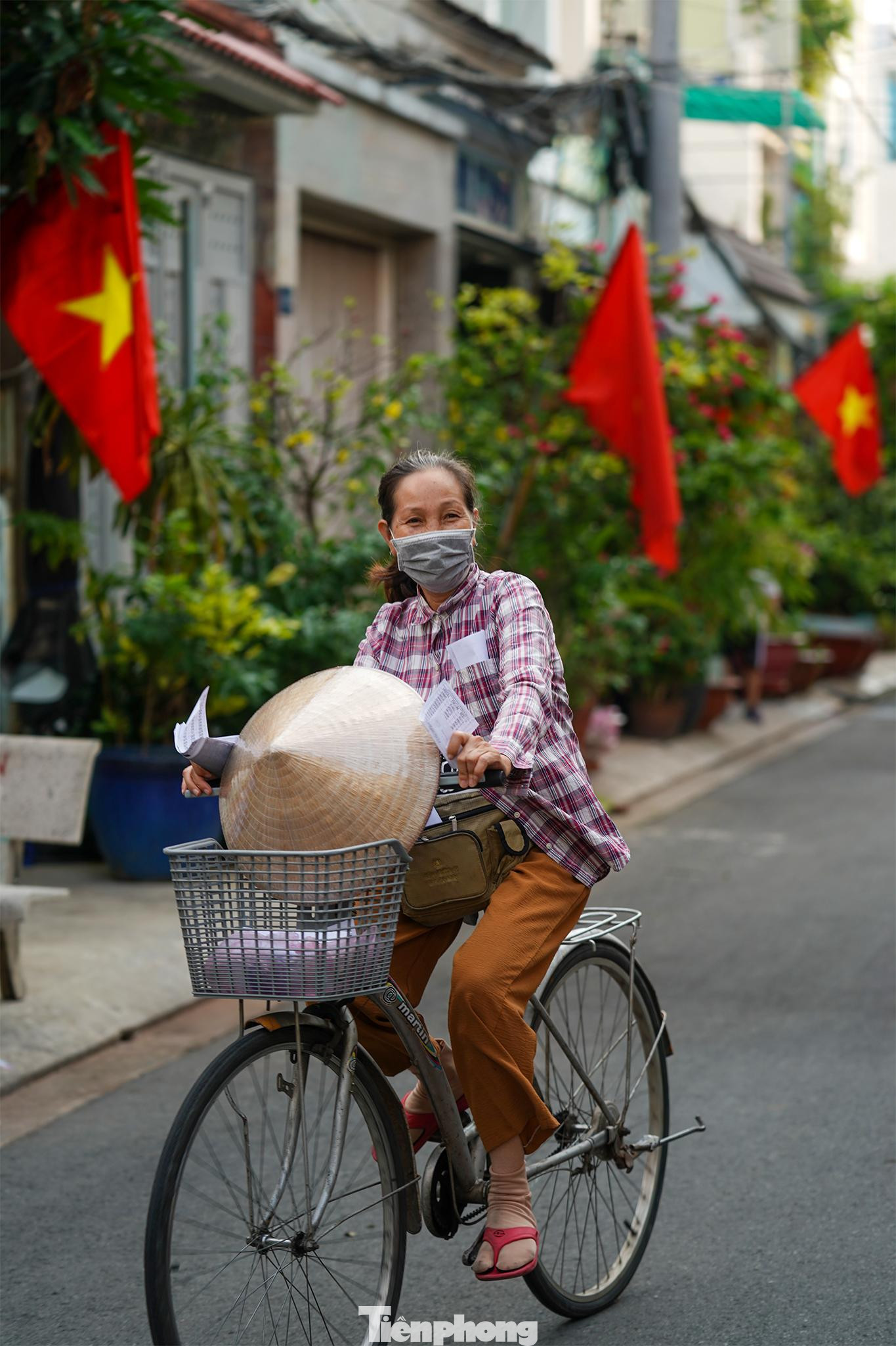 Trong một con hẻm nhỏ thuộc phường An Lạc A, quận Bình Tân, người phụ nữ bán vé số cười tươi chạy dưới hàng cờ. "Qua rồi những ngày giãn cách, bình thường mới lại rồi, được đi bán vé số rồi, quá hạnh phúc", bà Lê Thị Quỳnh, hành nghề bán vé số chia sẻ.