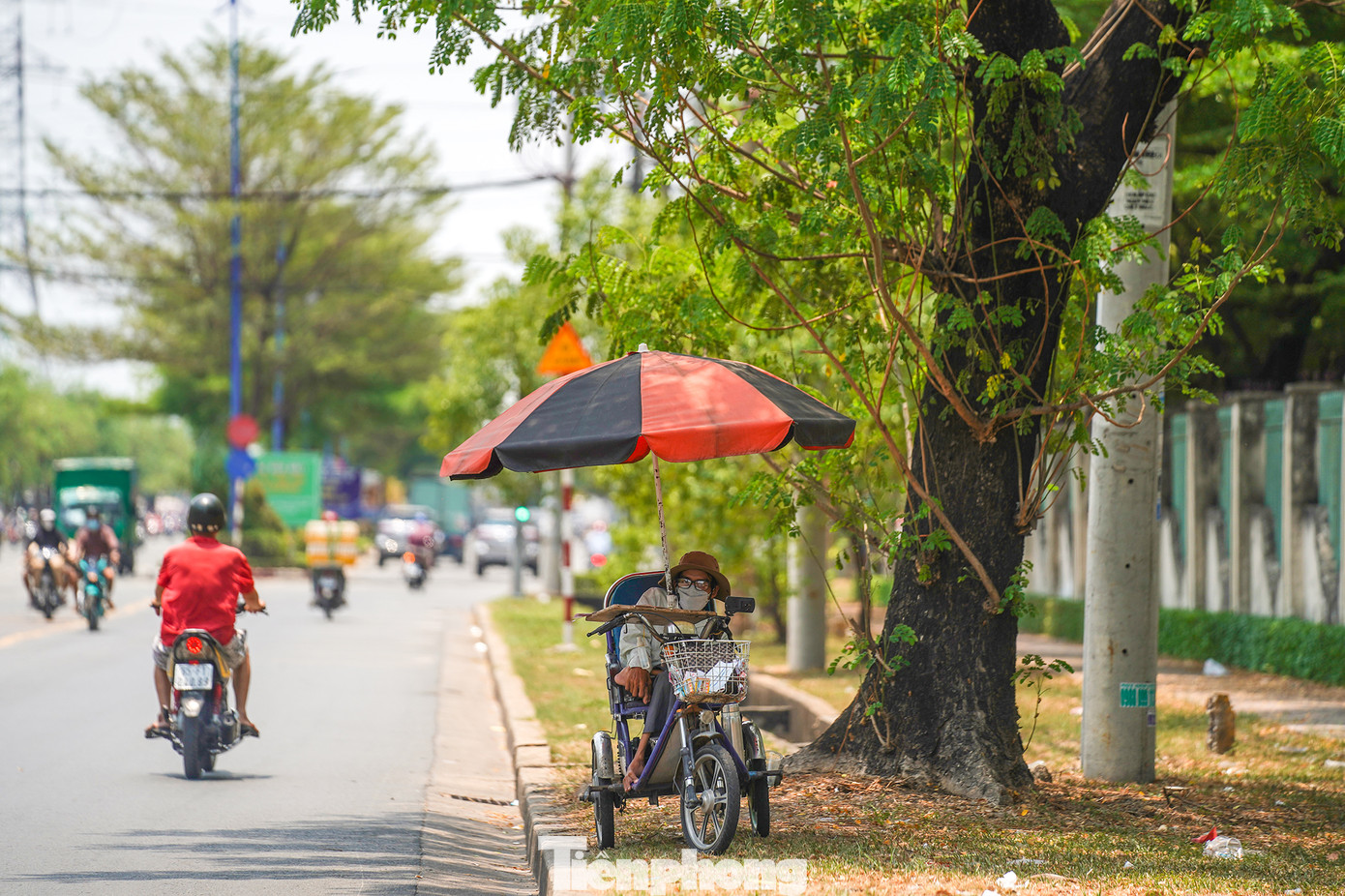 Một người bán vé số tuy đã chuẩn bị dù lớn nhưng vẫn phải tìm bóng râm để trú.