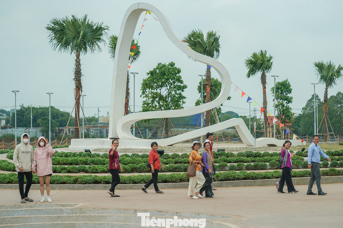 Một nhóm du khách đang dạo chơi tại khu vực trung tâm của công viên, nơi có biểu tượng câu chuyện trầu cau.