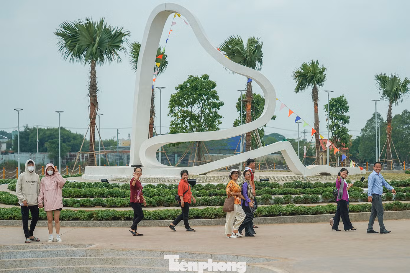 Một nhóm du khách đang dạo chơi tại khu vực trung tâm của công viên, nơi có biểu tượng câu chuyện trầu cau.