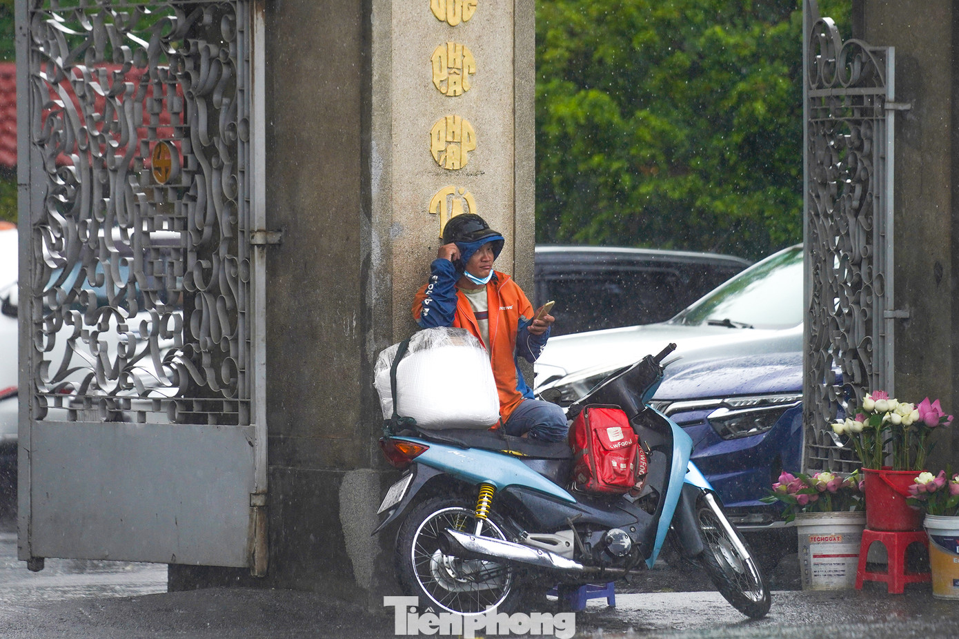 Một người giao hàng trú mưa trước cổng chùa Vĩnh Nghiêm.