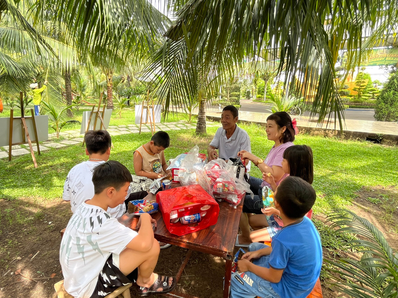 Một gia đình may mắn &quot;xí&quot; được chỗ ăn uống mát mẻ bên dưới những tán dừa.
