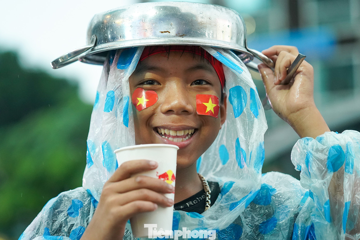 Một em nhỏ tận dụng chiếc nồi tạo âm thanh cổ vũ để che mưa. Một em nhỏ tận dụng chiếc nồi tạo âm thanh cổ vũ để che mưa.