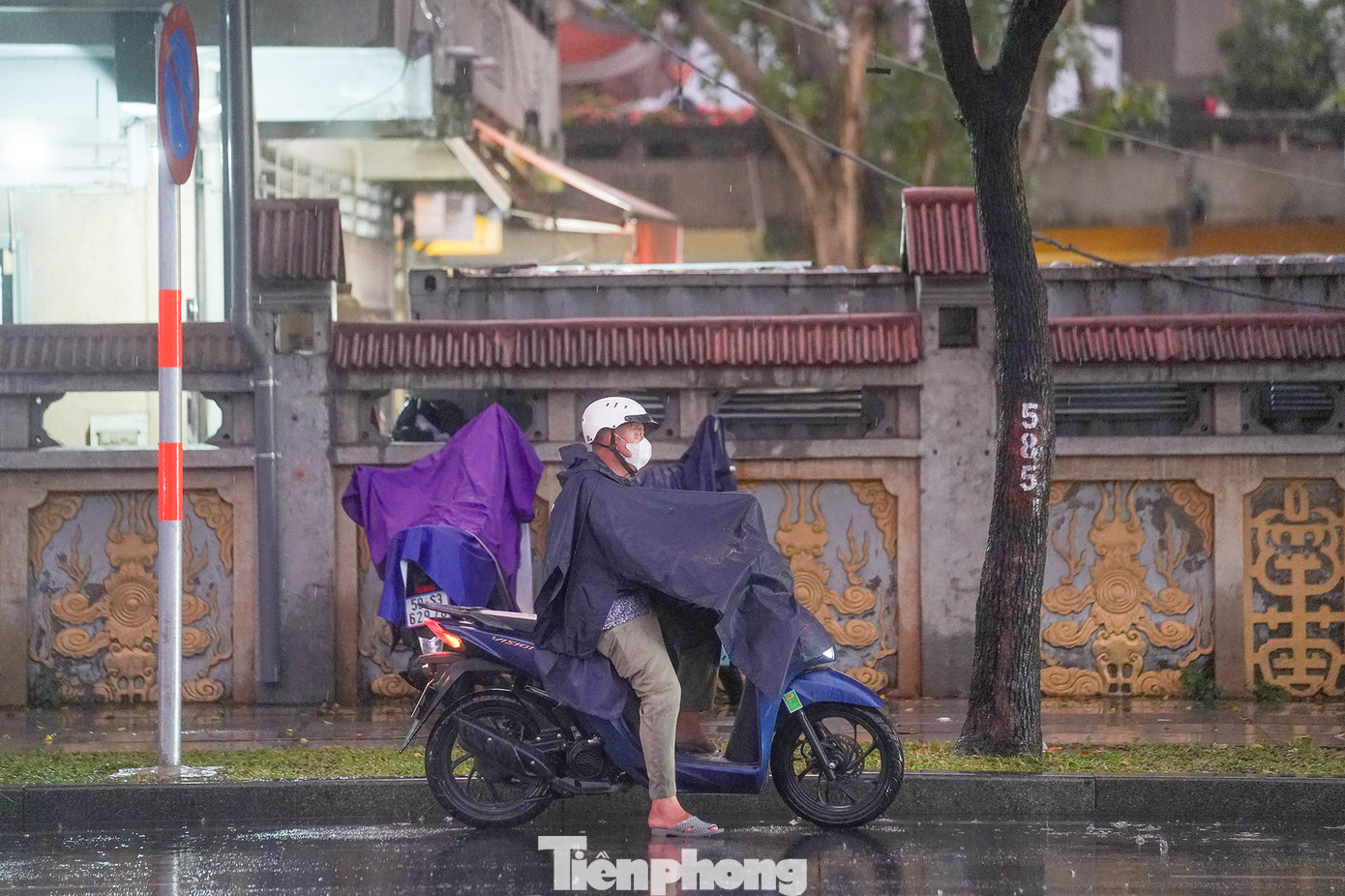 Một người đàn ông vừa dừng xe lại mặc áo mưa nhưng chưa đi vội vì tầm nhìn đang bị hạn chế khi ông vừa ra từ bãi xe chùa Vĩnh Nghiêm.