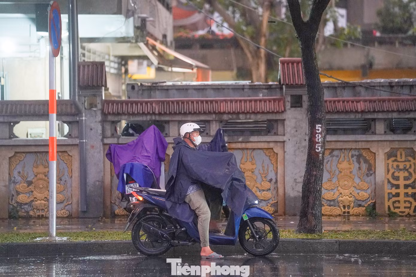 Một người đàn ông vừa dừng xe lại mặc áo mưa nhưng chưa đi vội vì tầm nhìn đang bị hạn chế khi ông vừa ra từ bãi xe chùa Vĩnh Nghiêm.