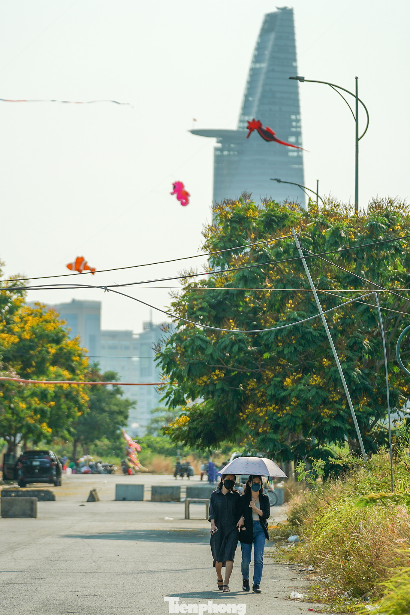 Hai bạn nữ đang làm việc tại một văn phòng công ty xây dựng vừa tản bộ dưới hàng điệp vàng.