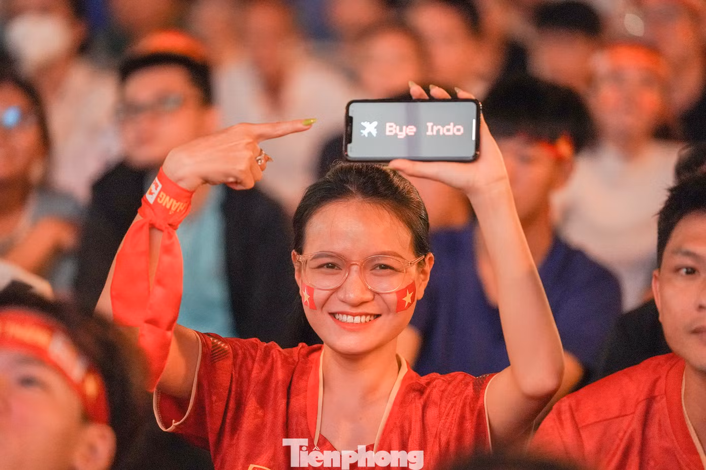 Một nữ cổ động viên giơ cao điện thoại tạm biệt đội tuyển Indonesia, chúc mừng đội tuyển Việt Nam tiến vào trận chung kết.