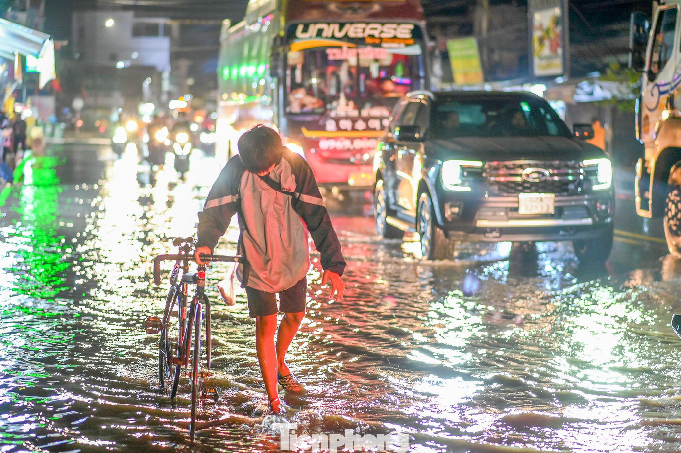 Một thiếu niên không thể đạp xe, phải lội bộ qua khu vực ngập nước.