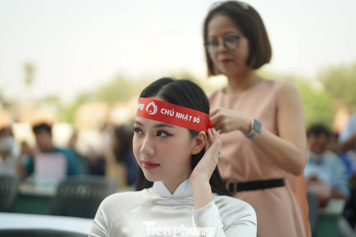 Người đẹp Phạm Thị Phương Quỳnh, top 5 HHVN 2020 đang được thành viên BTC hỗ trợ buộc chiếc băng đô lên đầu.