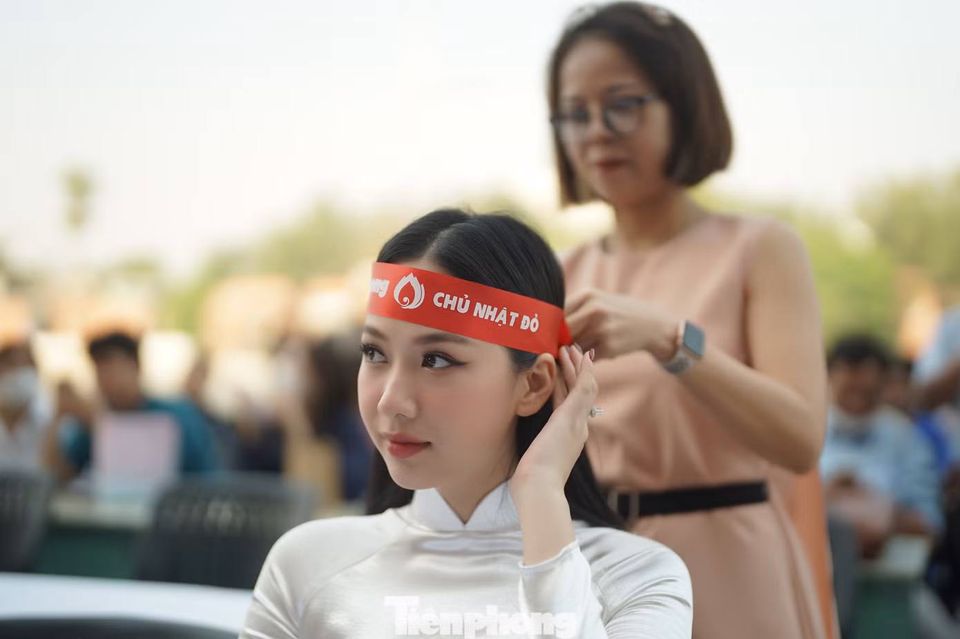 Người đẹp Phạm Thị Phương Quỳnh, top 5 HHVN 2020 đang được thành viên BTC hỗ trợ buộc chiếc băng đô lên đầu.