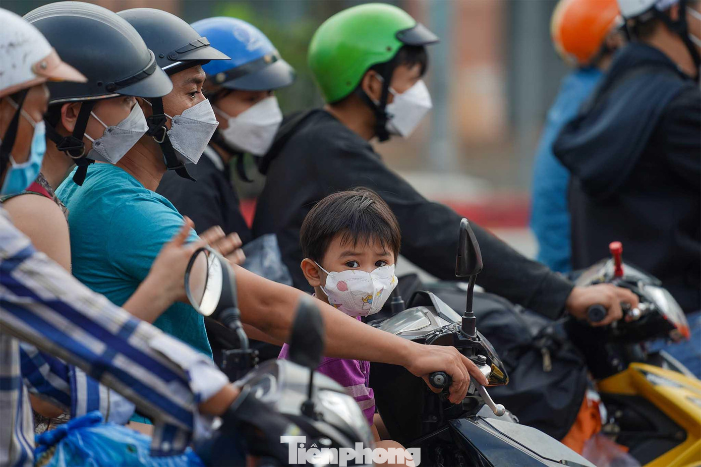 Một em bé nhìn ngơ ngác sau khi vừa tháo chiếc nón bảo hiểm trên đầu vì oi bức.