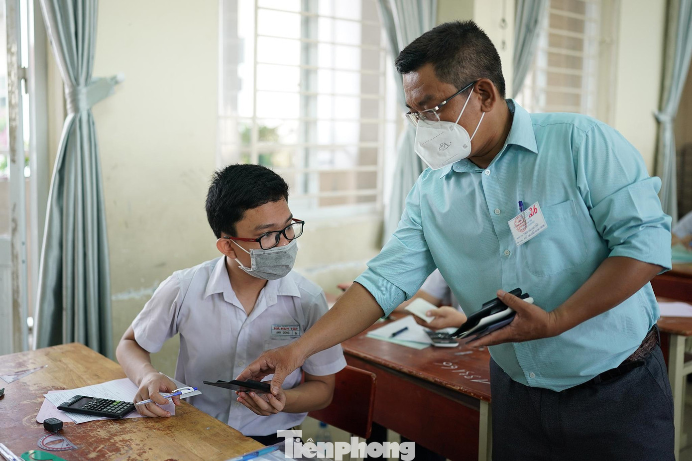 Một cán bộ coi thi đang tạm thu ốp lưng máy tính của một thí sinh.