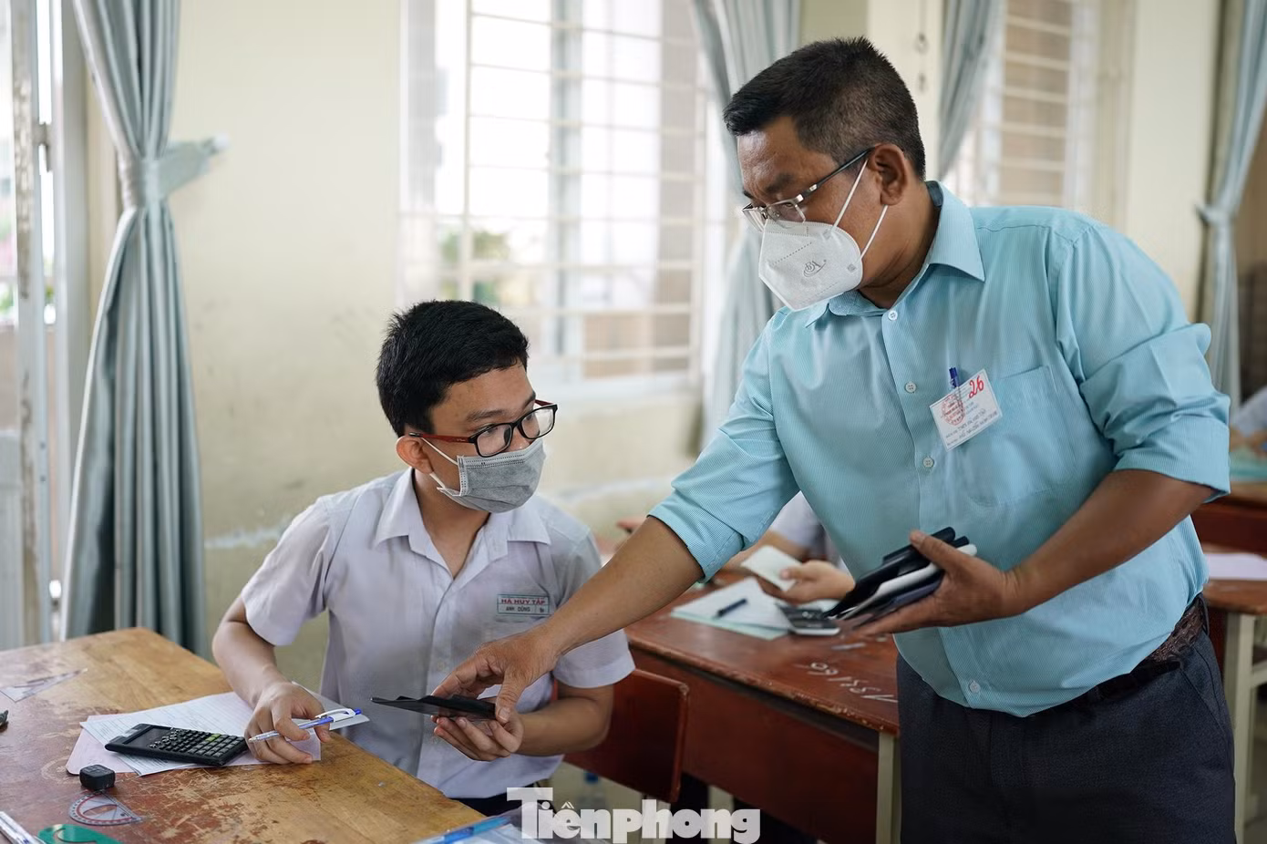 Một cán bộ coi thi đang tạm thu ốp lưng máy tính của một thí sinh.