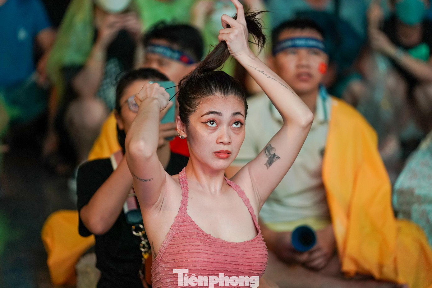 Một nữ khán giả buộc lại mái tóc ướt trong bộ đồ sũng nước mưa. Một nữ khán giả buộc lại mái tóc ướt trong bộ đồ sũng nước mưa.