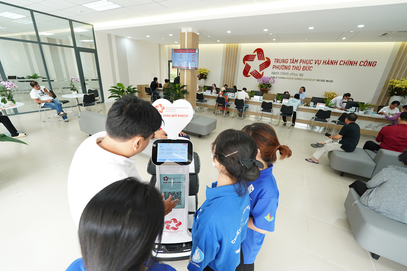 Trung tâm Phục vụ hành chính công phường Thủ Đức hiện có hai robot lễ tân. Trong đó, một làm nhiệm vụ phục vụ nước, kẹo, sọt rác, một làm nhiệm vụ mang hồ sơ, hướng dẫn người dân đến quầy làm thủ tục. Trong ảnh, chuyên gia đang hướng dẫn cách ra lệnh để robot dẫn đến quầy làm thủ tục.