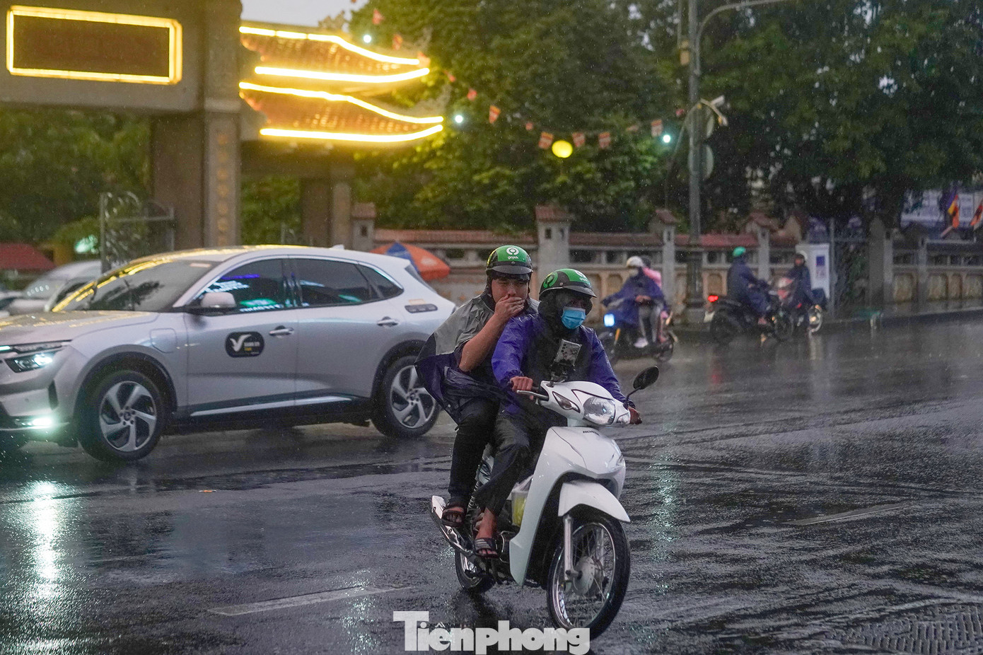 Một bác tài xe ôm và khách ướt sũng vì không kịp mặc áo mưa. Sáng và trưa 31/12, TPHCM cũng như Đông Nam bộ có nắng nóng. Nhiệt độ từ khoảng 10h đến 14h lên mức 33 - 34oC. Đến 15h, cơn mưa xuất hiện và 16h bắt đầu mưa to.