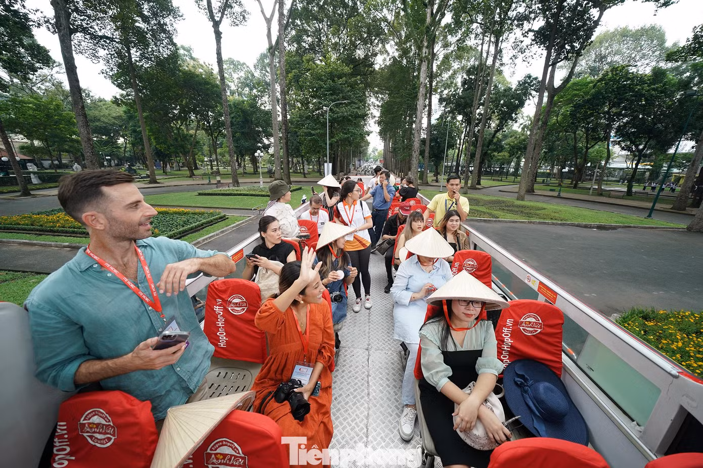 Du khách vẫy tay chào người dân đi tập thể dục buổi sáng ở công viên Tao Đàn.