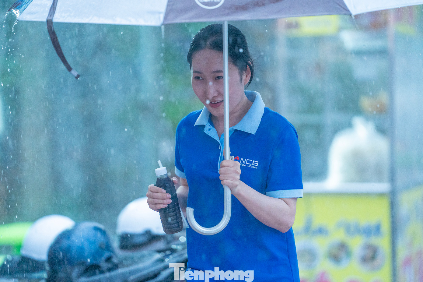 Mưa lớn bất chợt trong lúc đi mua nước sâm, nữ nhân viên này phải mượn ô che để quay lại nơi làm việc.