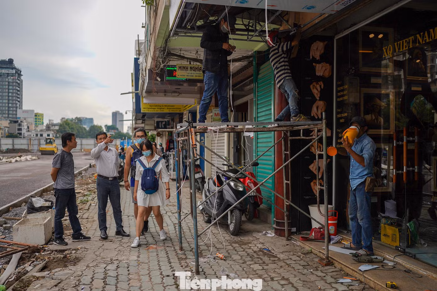 "Tôi làm ở cửa hàng thêu XQ hơn hai mươi năm. Nhờ công ty lớn nên có nguồn phí dự trữ để duy trì mặt bằng cộng với sự chia sẻ của chủ nhà. Sau khi thành phố mở cửa, tôi thấy hiện khách nội địa là chủ yếu. Sau thời gian dịch mình không sửa chữa được, giờ thêm thành phố dỡ rào chắn nên hôm nay cho thợ đến thi công lại để chuẩn bị đón khách. Chỉ mới mở nên cũng chưa ghi nhận tình hình buôn bán thực sự như thế nào", ông Trần Minh Kha (áo trắng, đứng chỉ tay) tâm sự.