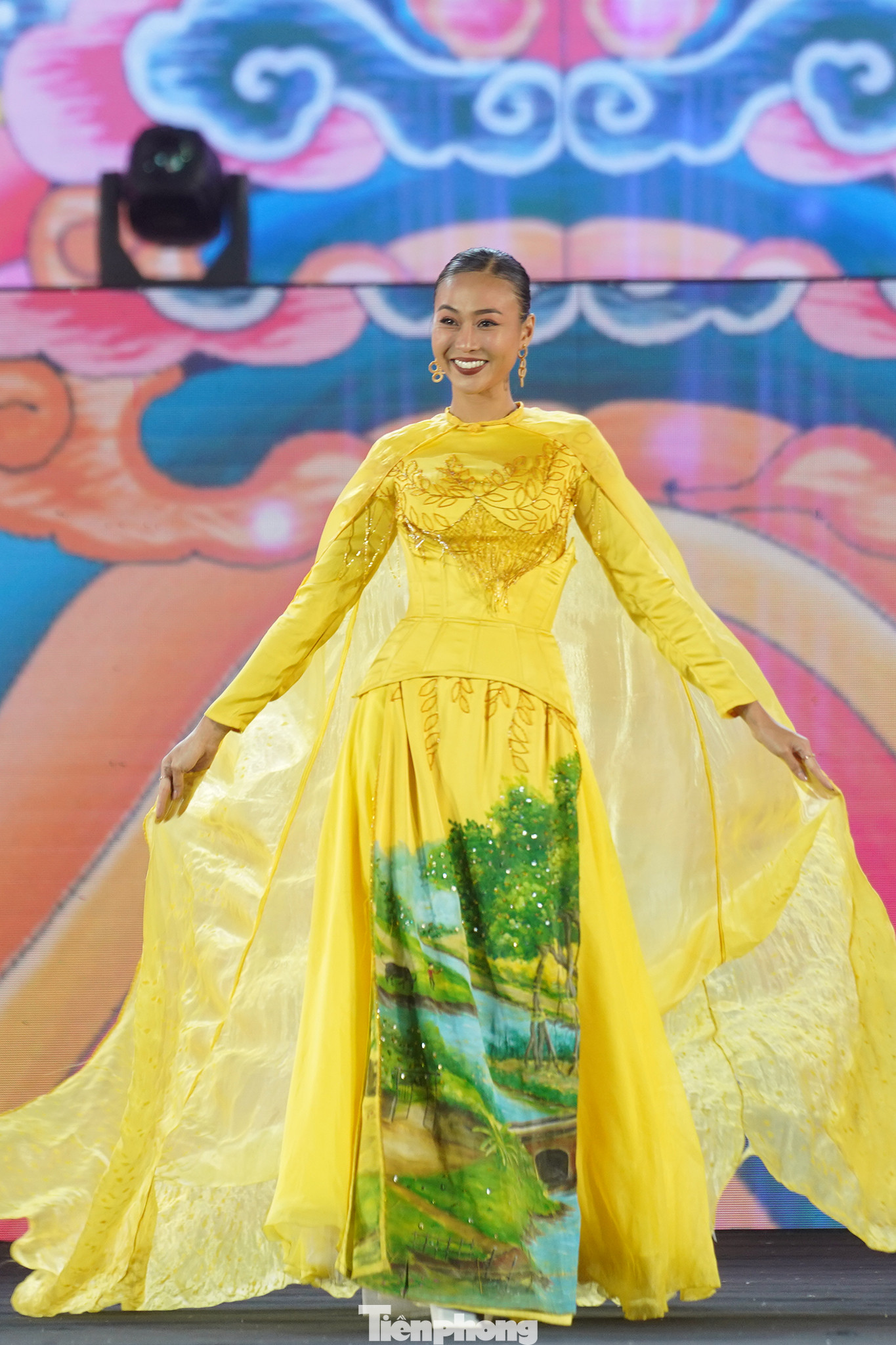 Nhà thiết kế Bảo Bảo mang đến sự kết hợp độc đáo giữa áo dài và áo bà bà trong bộ sưu tập Bức họa đồng quê. Phần tà kéo dài trên sân khấu, kết hợp sắc vàng của trang phục mang đến phần trình diễn đẹp mắt.