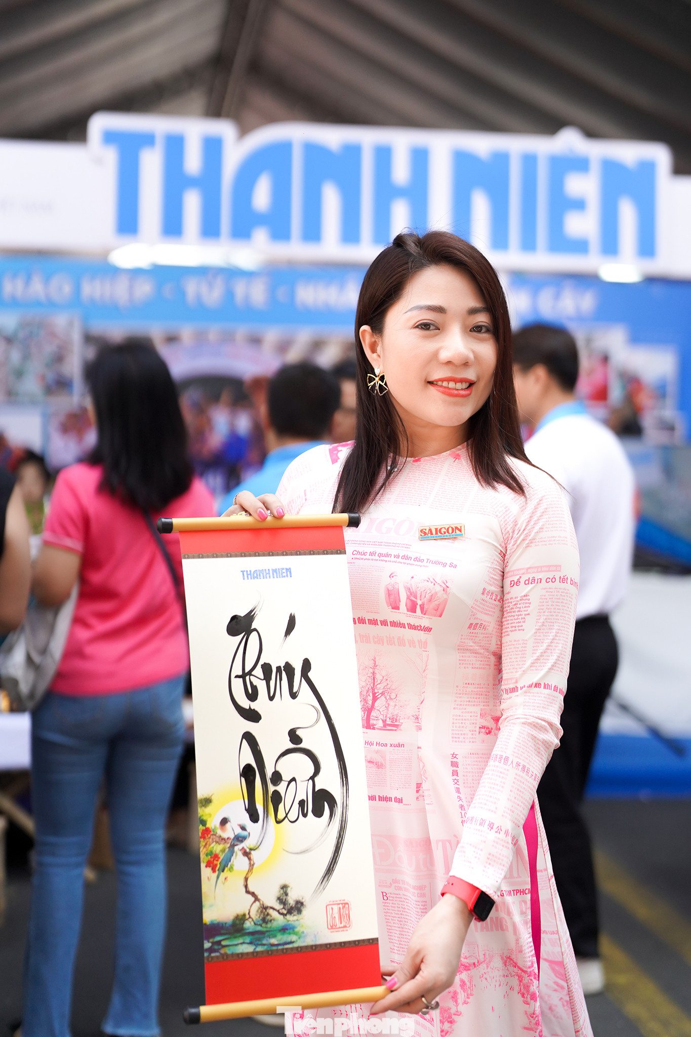 Chị Thuý Diễm, nhân viên phòng Quảng cáo- Phát hành báo SGGP thả dáng bên tấm thư pháp vừa được tặng từ gian báo Thanh Niên "hàng xóm".