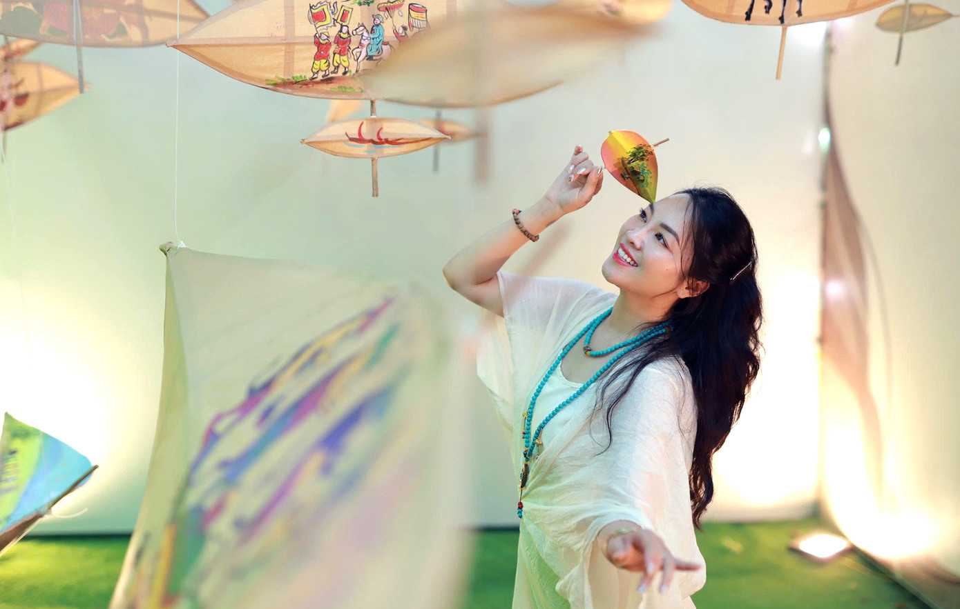 Cùng với những trang phục năng động ngày Hè, nhiều bạn trẻ đã diện mẫu áo dài truyền thống để tạo dáng với không gian diều. Nguyễn Văn Hải (sinh viên ĐHQG Hà Nội) cùng nhóm bạn đã cùng có hành trình trở về tuổi thơ với cánh diều, tiếng sáo vi vu giữa không gian xanh của bầu trời, ruộng đồng; cũng như những trò chơi ô ăn quan, kéo co. “Tôi không chỉ có dịp gặp lại những cánh diều vừa quen thuộc về kiểu dáng vừa mới lạ khi được trang trí bằng những bức tranh dân gian như đàn lợn âm dương, vinh quy bái tổ… Tôi cũng đã chụp ảnh bên những cánh diều này để lưu giữ kỷ niệm”, Hải nói. Ảnh: Đỗ Hưng