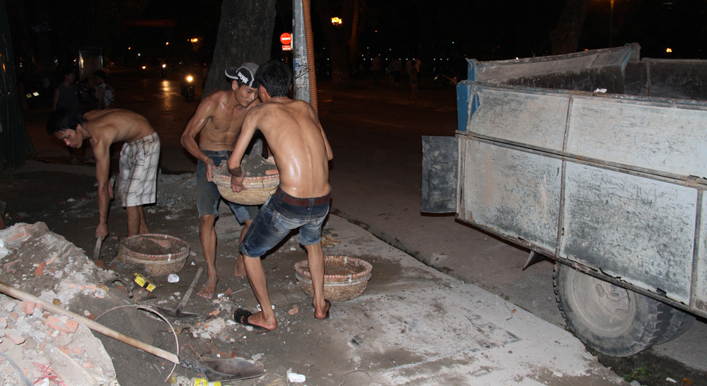 Ba người cùng nhau xúc. Mỗi khi có thúng đầy, một nam thanh niên dừng lại, đội thúng phế thải lên đầu, đổ vào thùng xe. Ảnh: Trường Phong