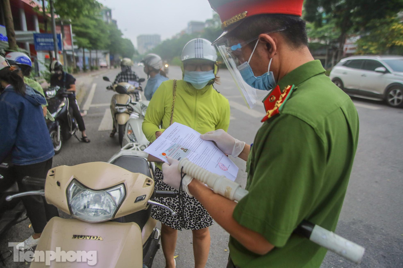 Một người phụ nữ xuất trình giấy đi đường và giấy tờ tùy thân, thẻ làm việc cơ quan được lực lượng nhắc nhở từ lần sau sẽ thêm lịch trực, lịch làm việc.