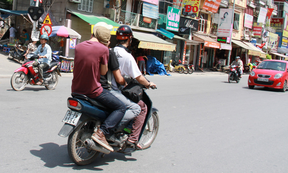 Một nam thanh niên lấy mũ che phần cổ tránh nắng nóng. Ảnh: Trường Phong