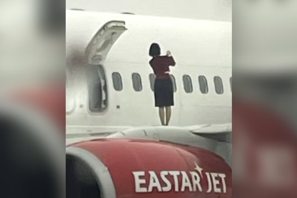 Các tiếp viên hàng không được nhìn thấy đang đi trên cánh máy bay và dường như đang chụp ảnh.