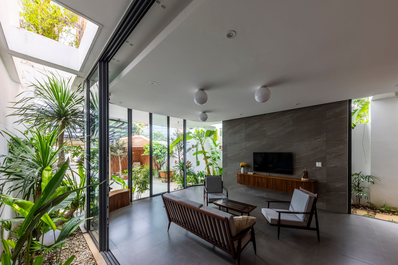 Cây xanh được bố trí hợp lý xung quanh không gian, kết hợp với ánh sáng tự nhiên từ cửa kính, tạo nên môi trường sống trong lành và thoáng mát. Thiết kế này không chỉ mang đến không gian thoải mái cho các hoạt động của gia đình mà còn tăng cường sự kết nối giữa cuộc sống con người với thiên nhiên, mang đến bầu không khí yên bình và thư giãn.