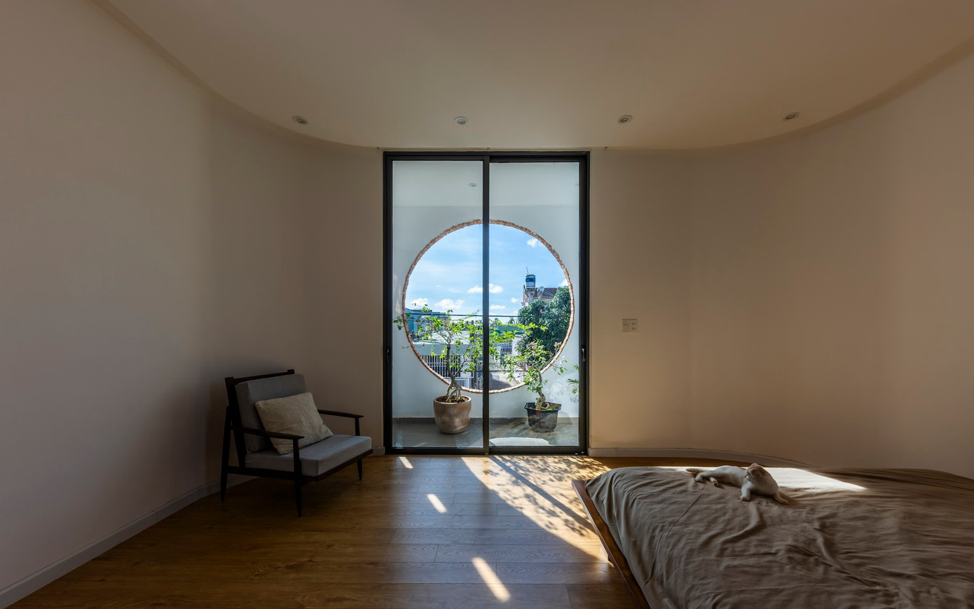 Phòng ngủ của bố mẹ được thiết kế theo phong cách tối giản, chú trọng vào sự thoải mái và yên tĩnh. Điểm nhấn của căn phòng là cửa sổ tròn lớn, mở ra tầm nhìn rộng ra quang cảnh bên ngoài.