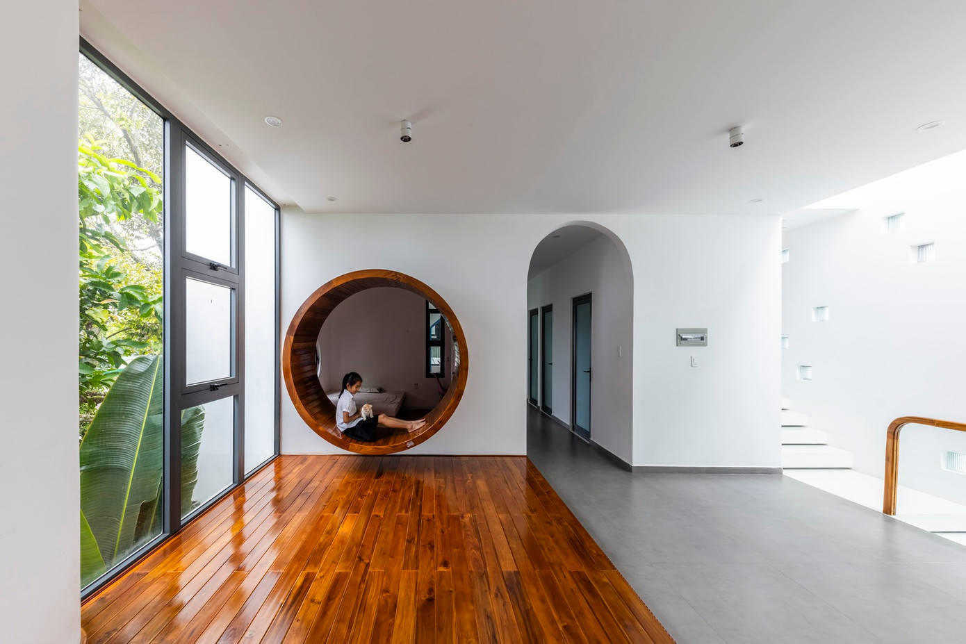 Ánh sáng tự nhiên tràn ngập căn phòng, kết hợp với tông màu trung tính như trắng, nâu, xám tạo nên không gian thanh bình và ấm áp. Nội thất được sắp xếp đơn giản nhưng thanh lịch, với một chiếc ghế đơn gần cửa sổ, tạo nên không gian lý tưởng để thư giãn hoặc đọc sách.