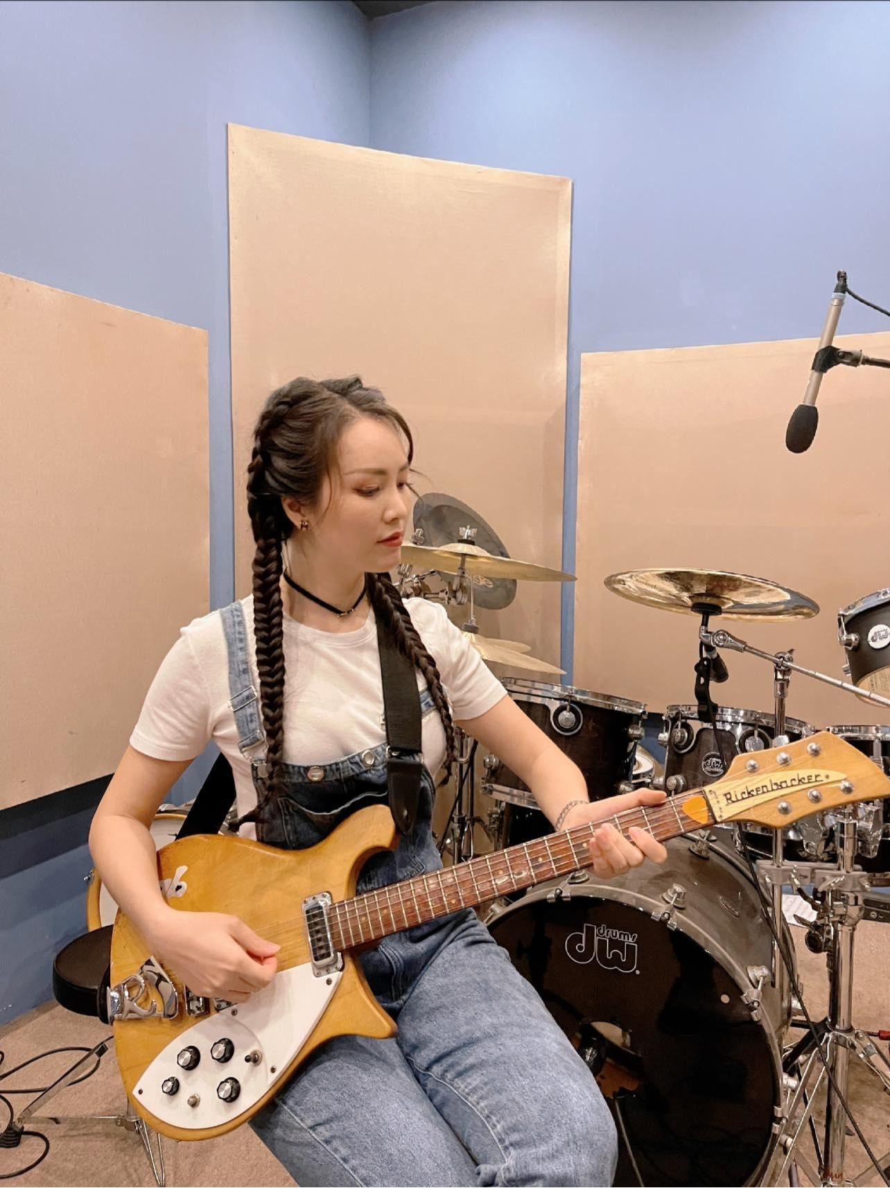 Á hậu Thuý Vân hoá thân thành cô gái trẻ trung với tóc tết bím hai bên, trổ tài chơi đàn guitar.