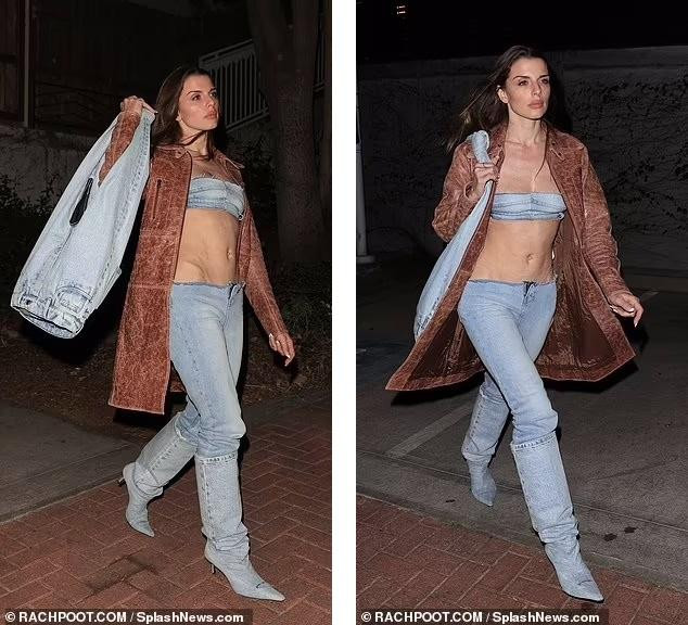 Người đẹp sinh năm 1990 nổi bật giữa đêm với nguyên set denim, bao gồm áo khoác nâu, áo quây, quần cạp trễ không lưng quần, boot cao cổ và túi xách biến tấu hình quần jean (giá 700 bảng Anh ~ 21 triệu đồng).