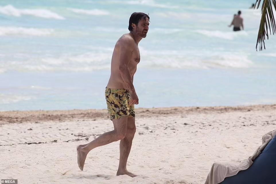 Trong khi đó, em trai "Người Dơi" mặc quần bơi màu vàng họa tiết hoa, lộ thân hình rắn rỏi tuổi U50.