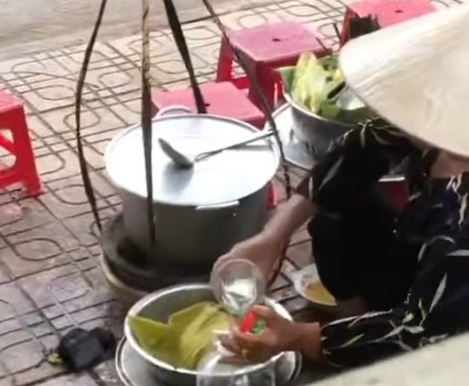 Bà H.T.T đổ nước thừa của khách vào bình. Ảnh cắt từ clip.