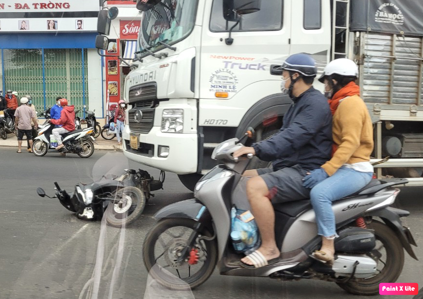 Xe máy nằm dưới gầm xe tải