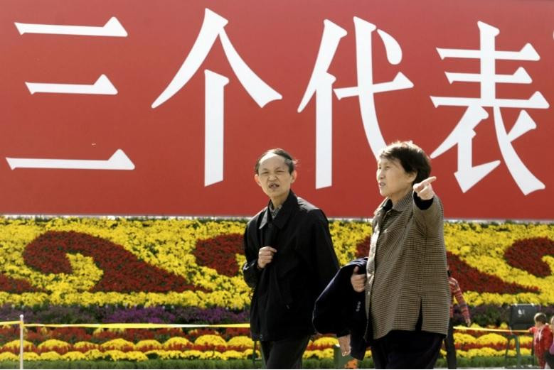 Người dân đi qua tấm biển in khẩu hiệu "Ba đại diện" năm 2003. (Ảnh: AP) Người dân đi qua tấm biển in khẩu hiệu "Ba đại diện" năm 2003. (Ảnh: AP)