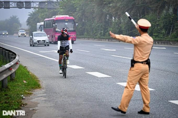 Lực lượng chức năng nhắc nhở người đàn ông ngoại quốc đạp xe vào làn ô tô. (Ảnh: Mạnh Quân).