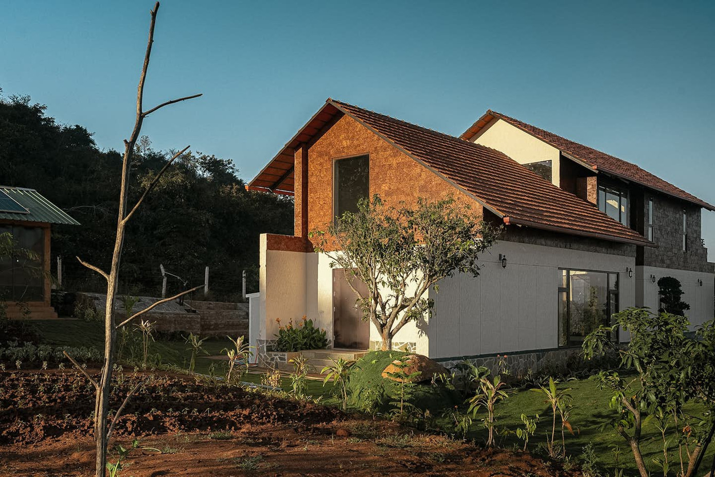 Kiến trúc nổi bật với mái ngói dốc truyền thống, cây xanh được bố trí xen kẽ với thảm cỏ và vườn rau nhỏ.