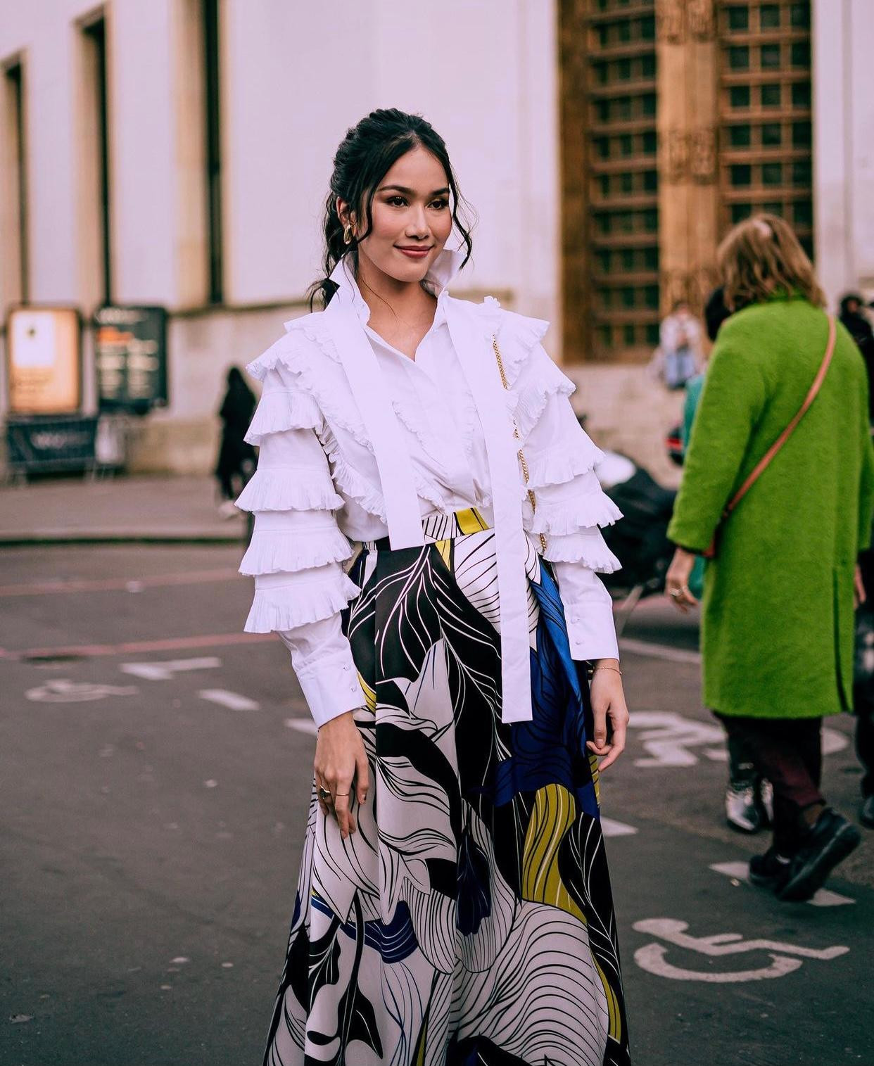 Trang phục của cô là sự kết hợp giữa chân váy nhiều màu sắc và áo sơ-mi trắng xếp ly đẹp mắt. Trang phục của cô là sự kết hợp giữa chân váy nhiều màu sắc và áo sơ-mi trắng xếp ly đẹp mắt.